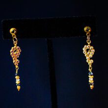 Luxury asymmetrical 18K gold earrings with diamonds, rubies, and blue sapphires.