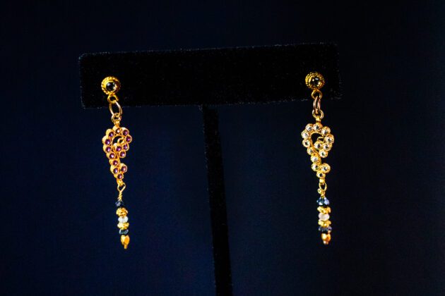 Luxury asymmetrical 18K gold earrings with diamonds, rubies, and blue sapphires.
